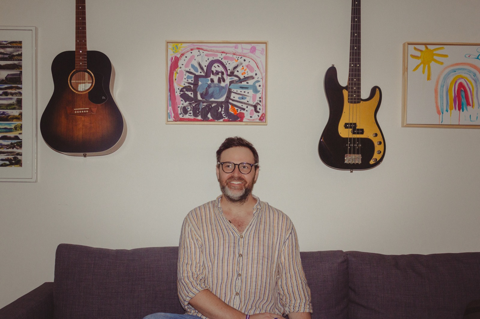 Jack Carty — press photo, striped shirt, guitars on wall
